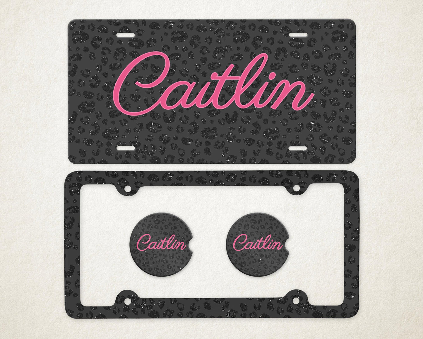 May include: A license plate and car coasters set. The license plate and coasters have a black leopard print design with the name "Caitlin" in pink script. The license plate frame is black.